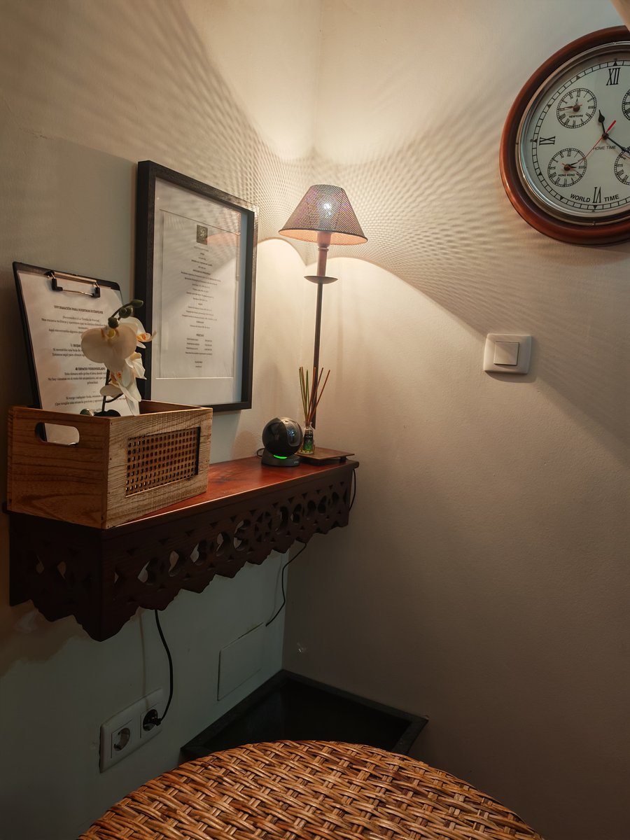 El hall de entrada de la casa: la estantería de madera con la lámpara y el reloj de pared